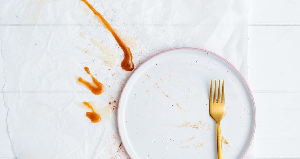 gold fork on top of empty white plate