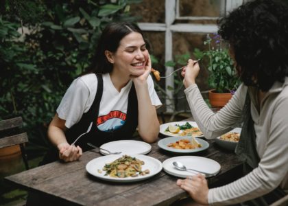 woman feeding girlfriend with fried seafood in garden